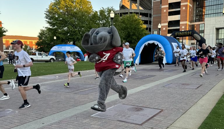 Big Al running down the Walk of Champions at the 2023 Crimson Couch to 5K event.