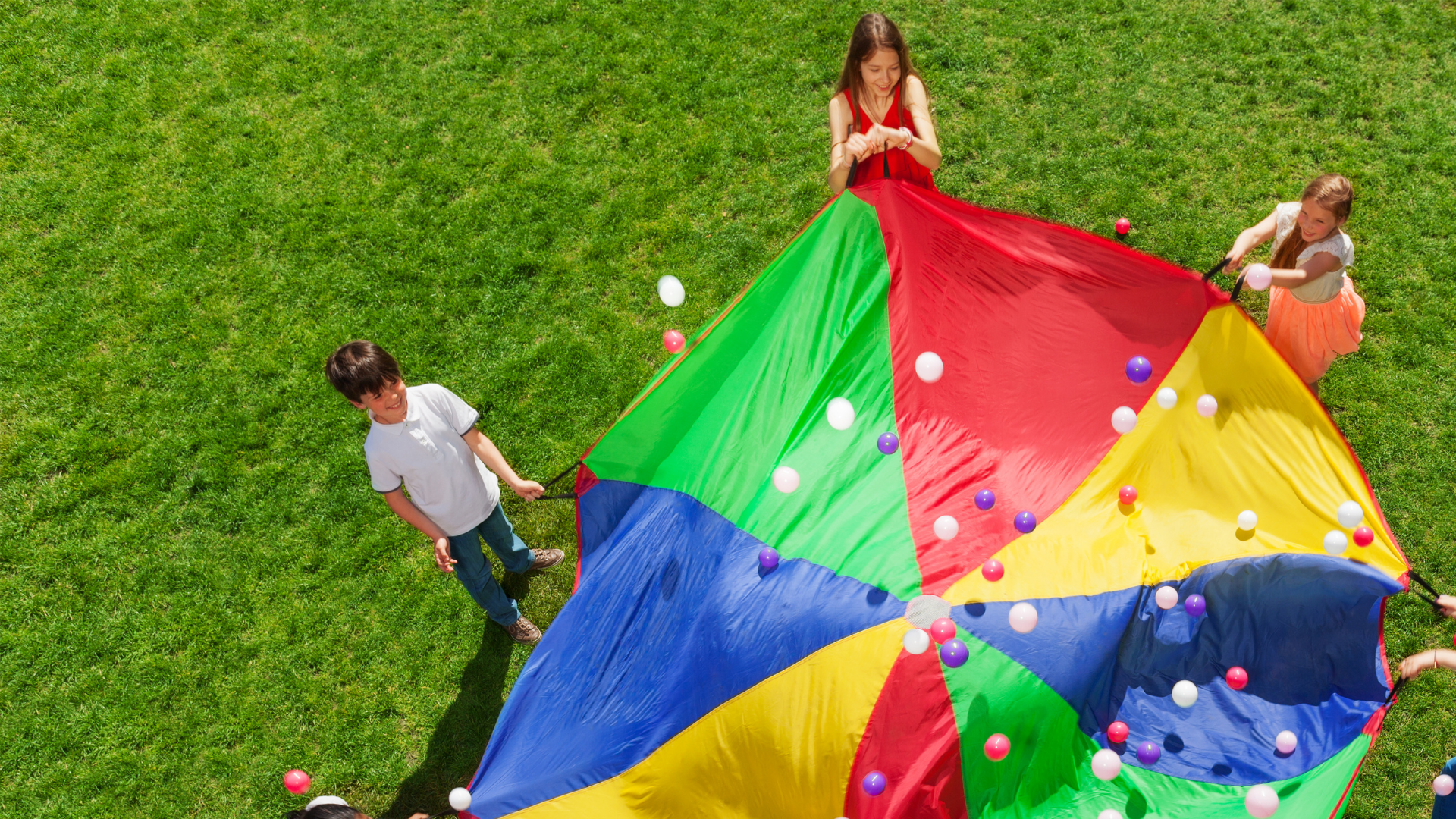 Kids around a colorful parachute