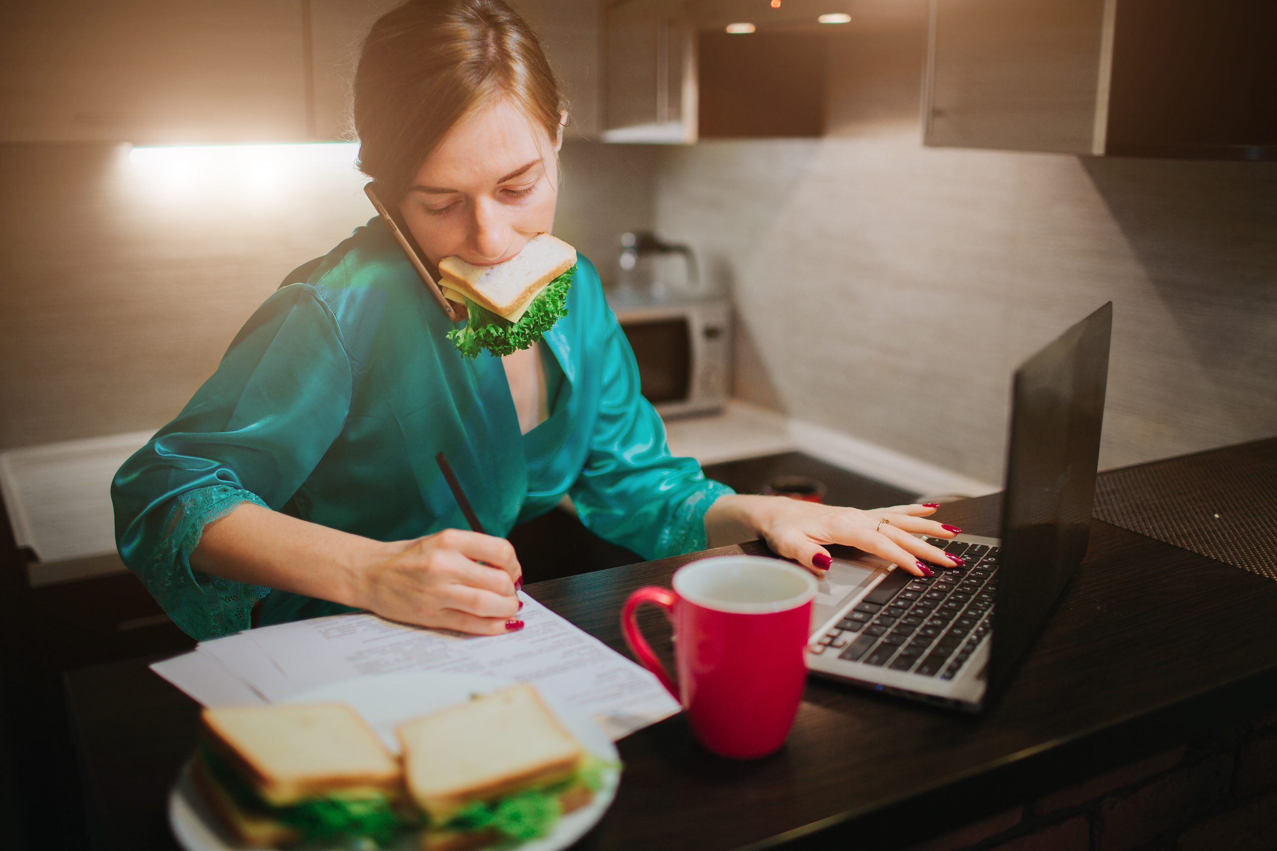 Busy woman eating, drinking coffee, talking on the phone, working on laptop at the same time. Businesswoman doing multiple tasks. Multitasking business person. Freelancer works at night.