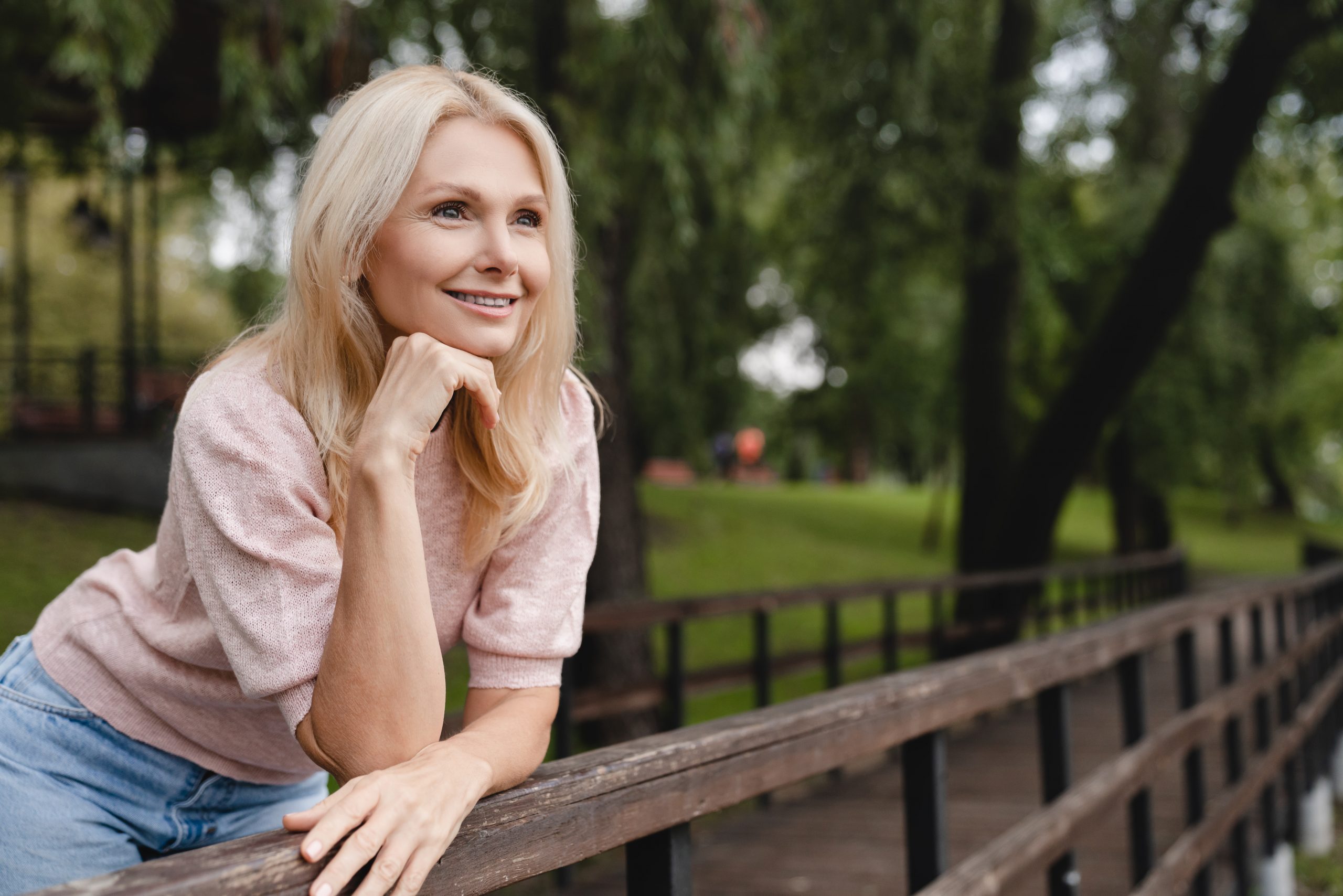 Dreamy pensive caucasian mature blonde woman walking relaxing resting in city park forest spending free time in woods