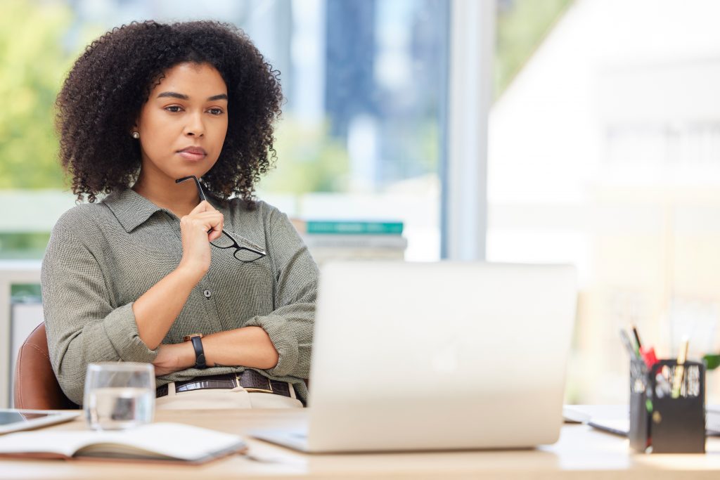Business laptop, thinking and black woman in office trying to solve problem. Idea, focus and female employee from South Africa with computer contemplating solution, pensive or lost in thoughts alone