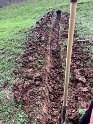 Shovel sticking out of dirt with a deep divot going through grass