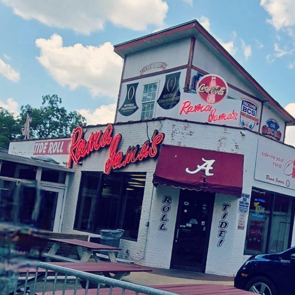 white building with red awning and alabama script A. Red rama jama's neon sign on the front