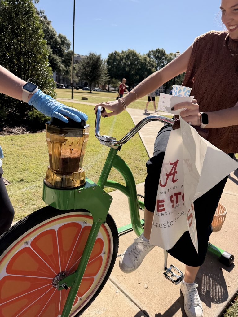 a women sits on a stationary bike that powers a blender at the front to make a smoothie