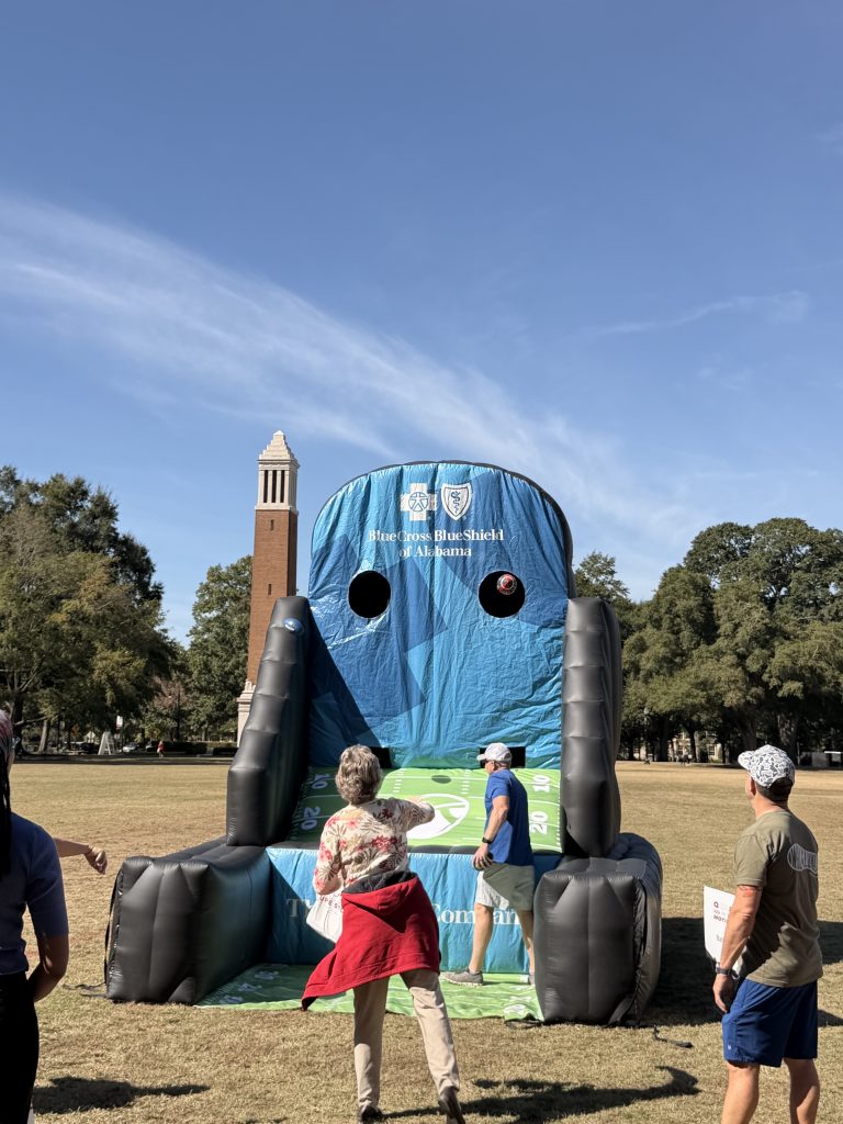 A group of people look at an inflatable football throw structure outdoors