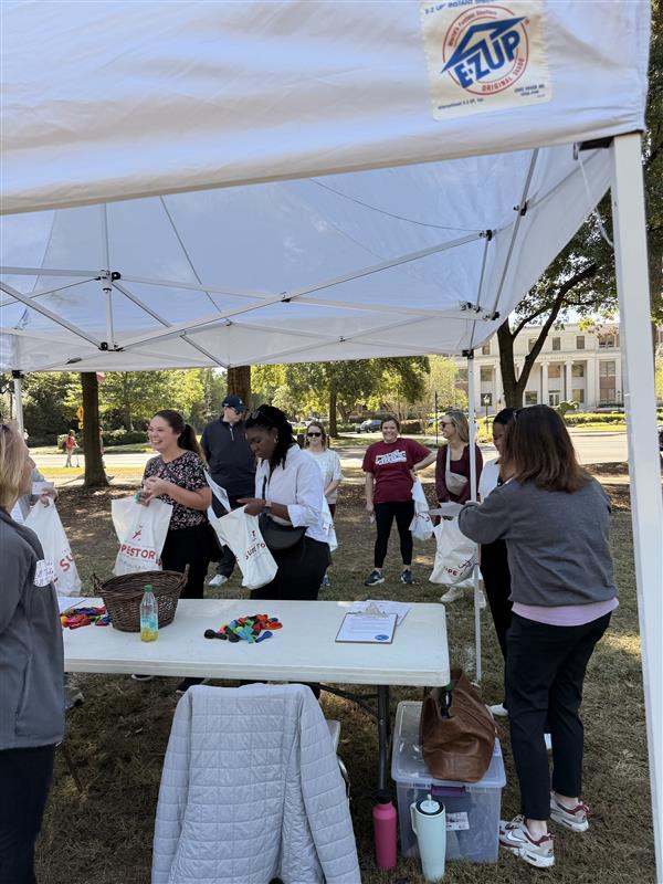 a group of people gather handouts from a table about deep breathing to place in their plastic bags 