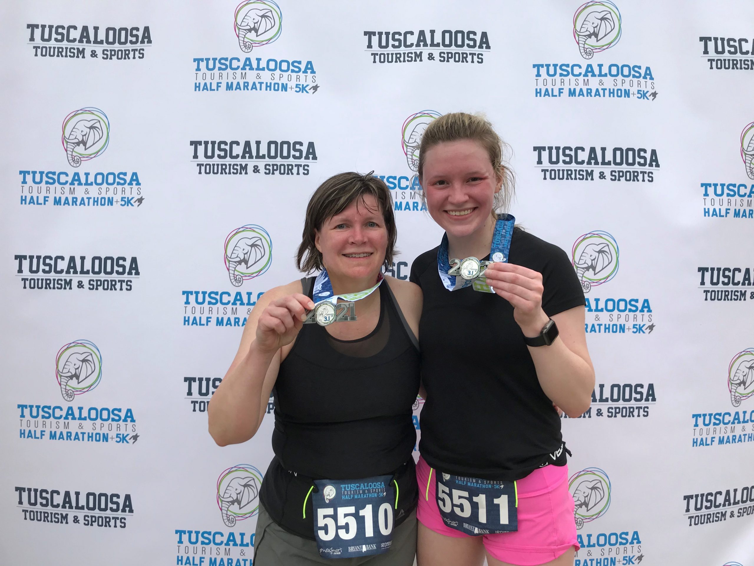 two women holding their medals at a 5K race